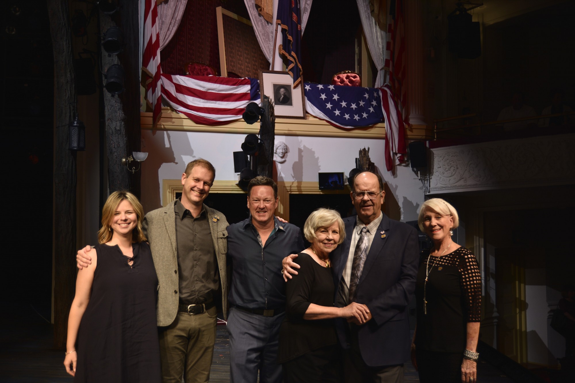 Six people stand arm in arm in front of the presidential box at Ford's Theatre.
