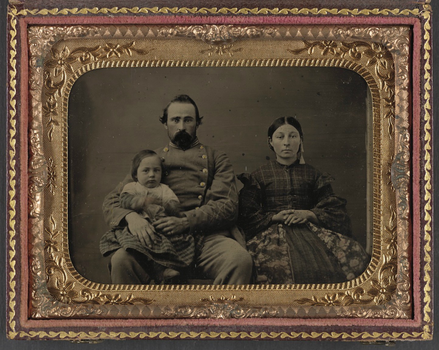 Framed black and white image of a man, woman and child. The man wears a confederate army uniform.