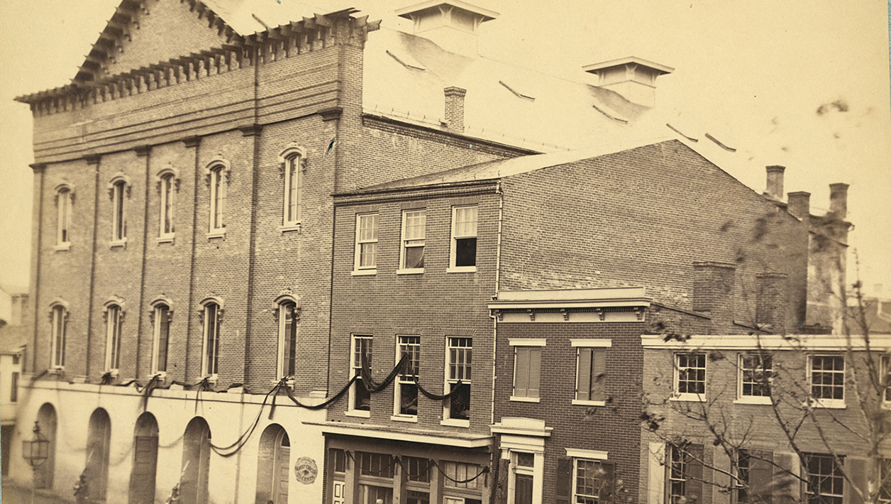 Sepia photograph of Ford's Theatre with black ribbon draped from the windows.