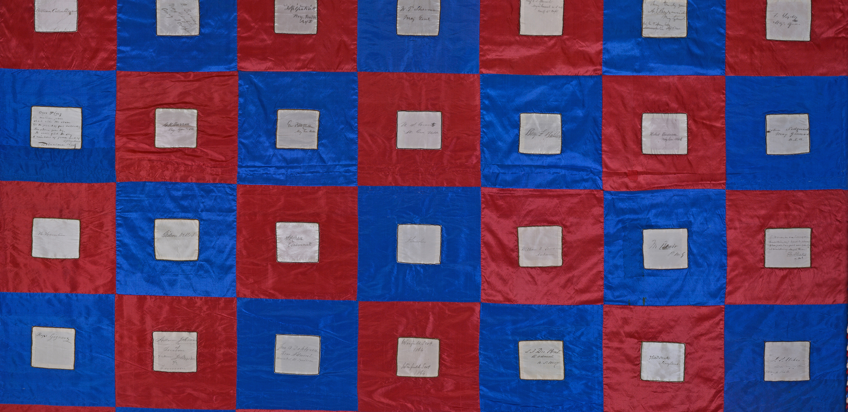 Photograph of a blue and red checkerboard quilt, with a signed piece of cloth sewn into each square.