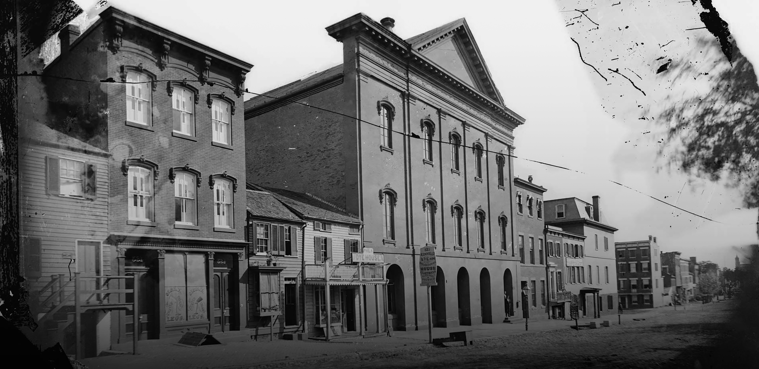 Black and white photograph of the exterior of Ford's Theatre and the rest of 10th street as it looked in the 19th century.